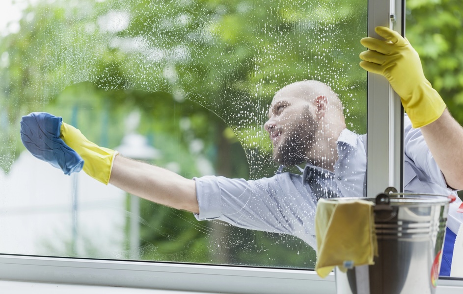 Professionelle Glasreinigung – Reinigungskraft säubert sorgfältig ein Fenster von außen.