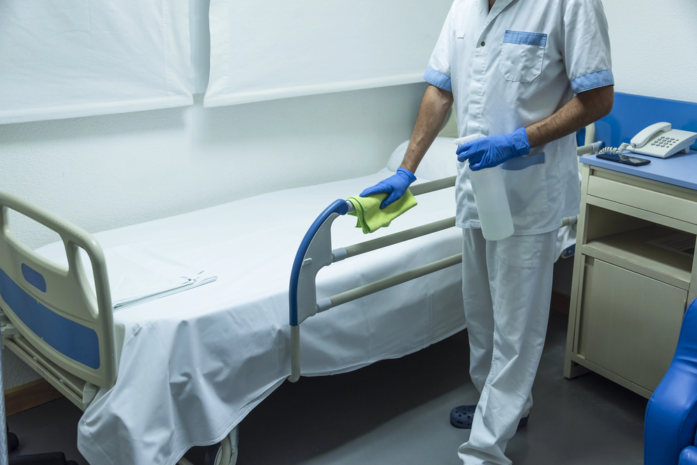 Professionelle Praxisreinigung – Reinigungskraft desinfiziert ein Bett in einer medizinischen Praxis.
